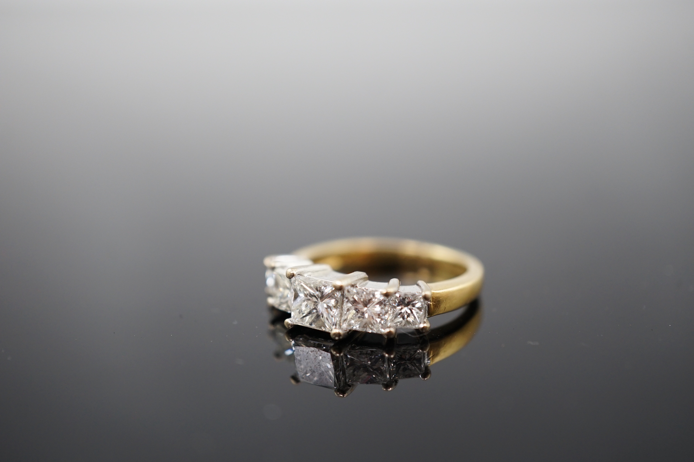 A modern 18ct gold and graduated five stone princess cut diamond set half hoop ring